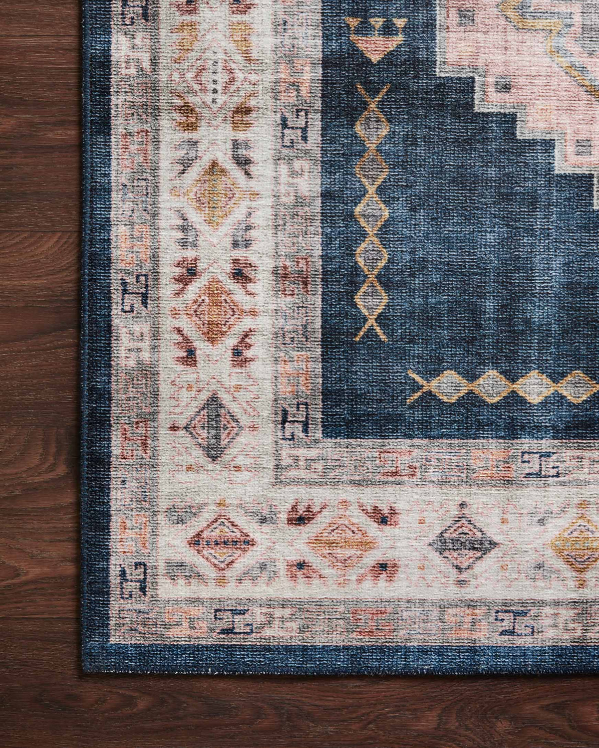 Close view of denim blue rug pattern with blush and ivory geometric details