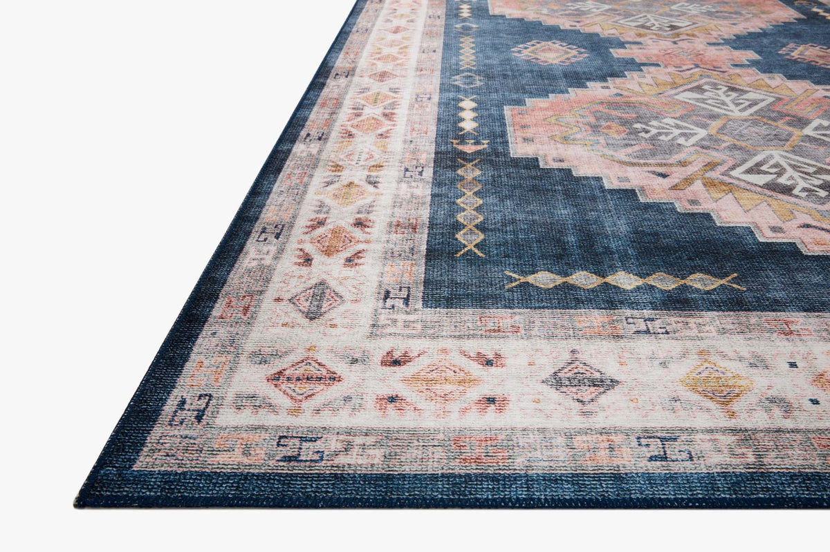 Denim blue corner rug with faded blush medallion, intricate geometric border, and motifs