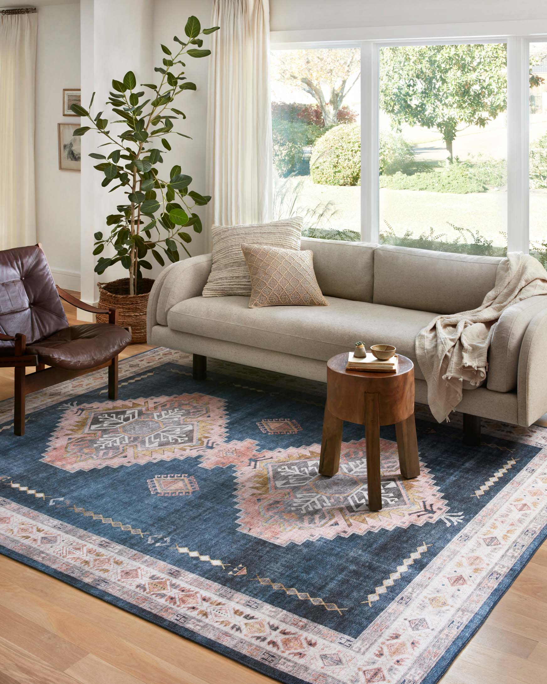 Denim blue traditional area rug with blush, ivory, and navy geometric border