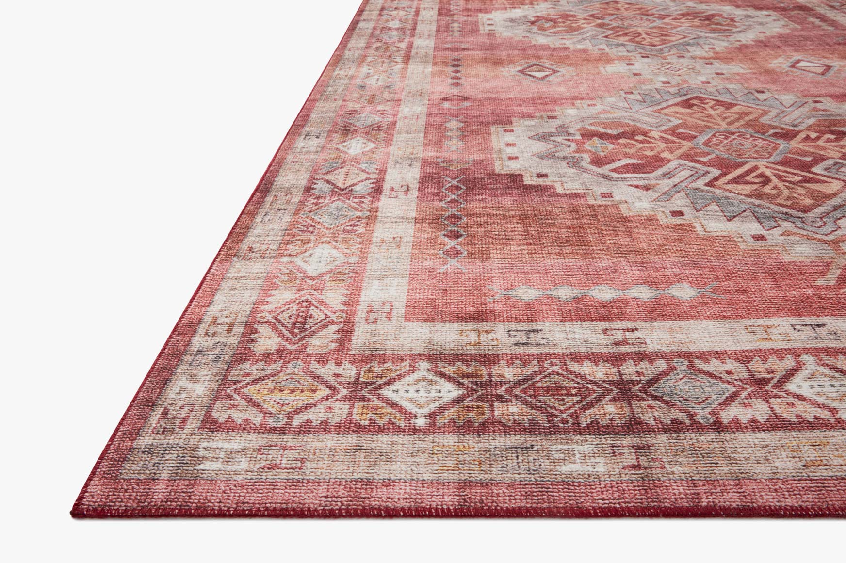 Close view of rust red rug corner with ivory bands, geometric patterns, and border.