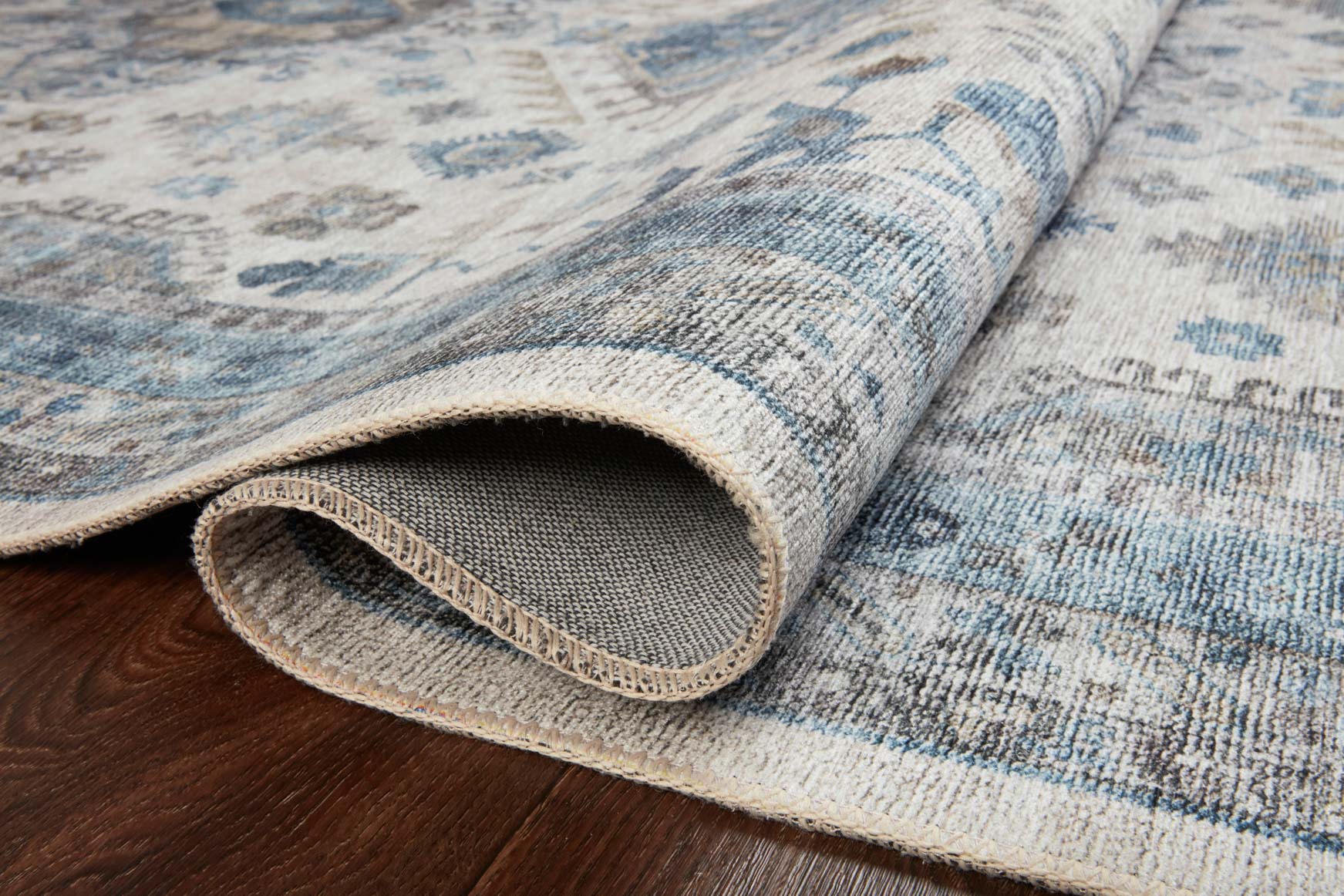 Close-up of ivory and ocean blue rug pile with rolled edge and textured weave