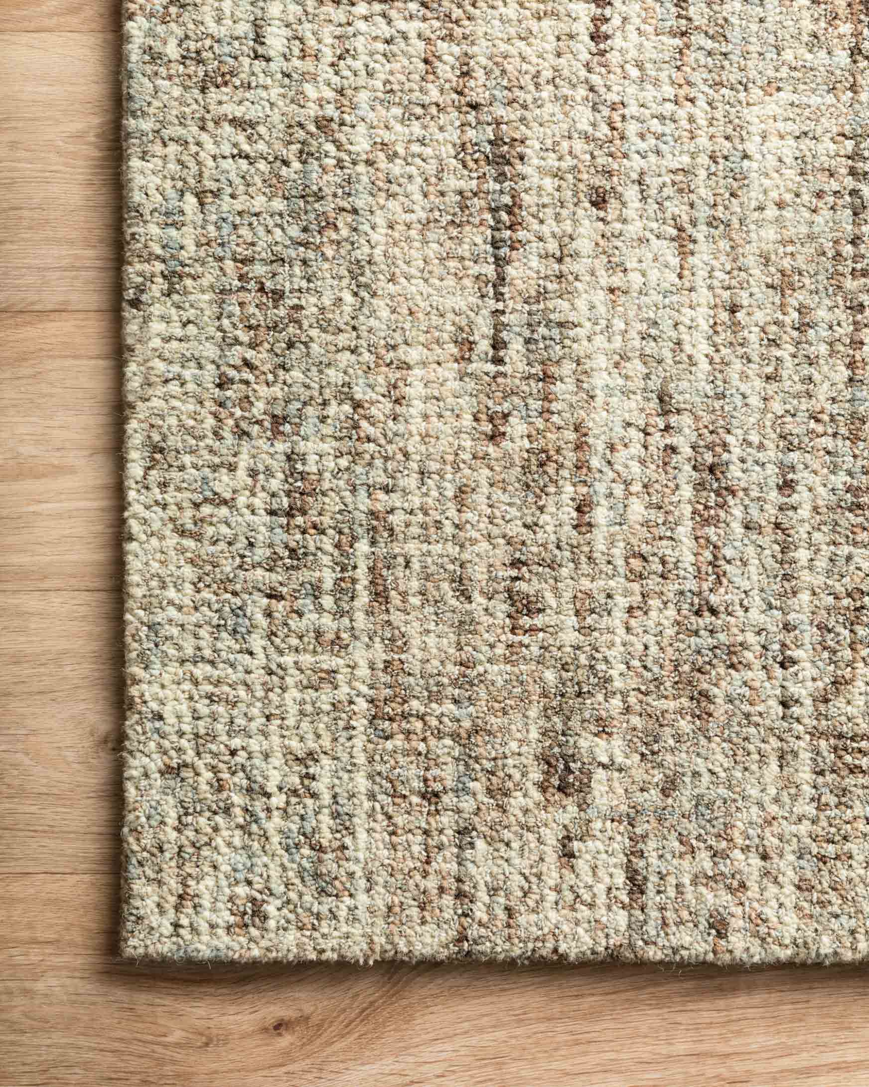 Hand-tufted rug close-up with speckled beige pile and vertical mocha abstract strokes.