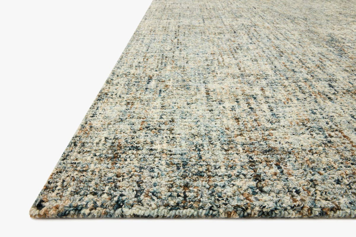 Hand-tufted area rug corner with blue and sand woven texture and low pile