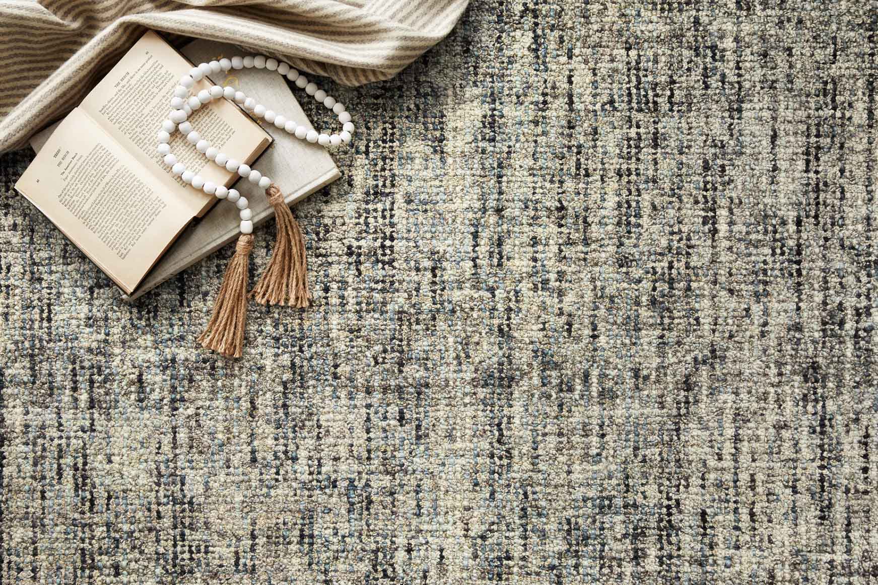 Close-up hand-tufted rug surface with blue, sand, and dark speckled yarns