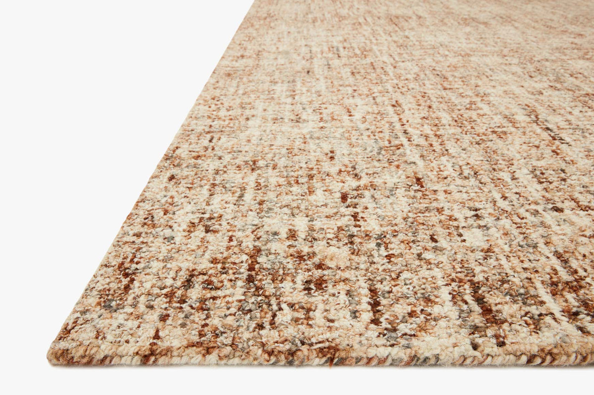 Rust-and-charcoal speckled rug corner with low pile and textured border edge