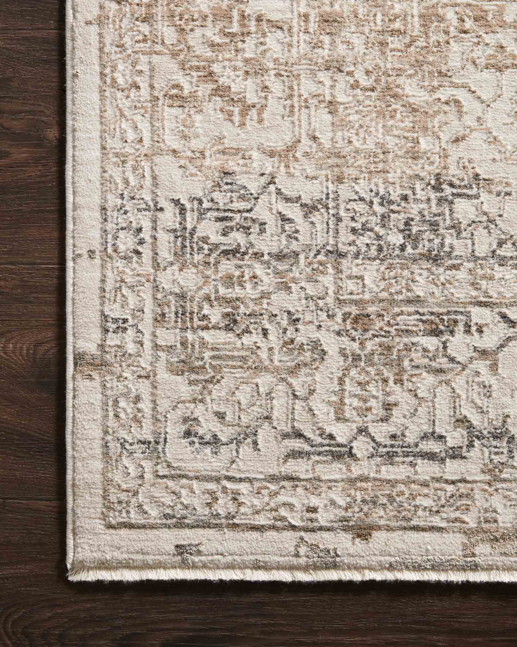 Beige and grey rug corner detail with ornate geometric motif and textured pile