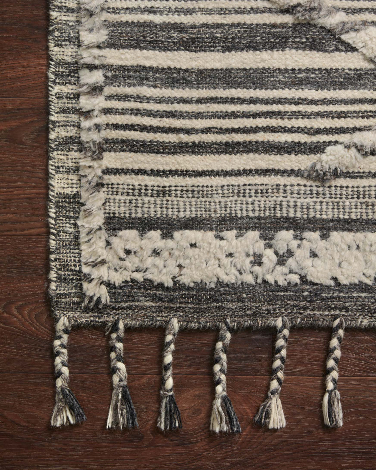 Hand-knotted rug edge close-up in ivory and charcoal stripes with tassel fringe