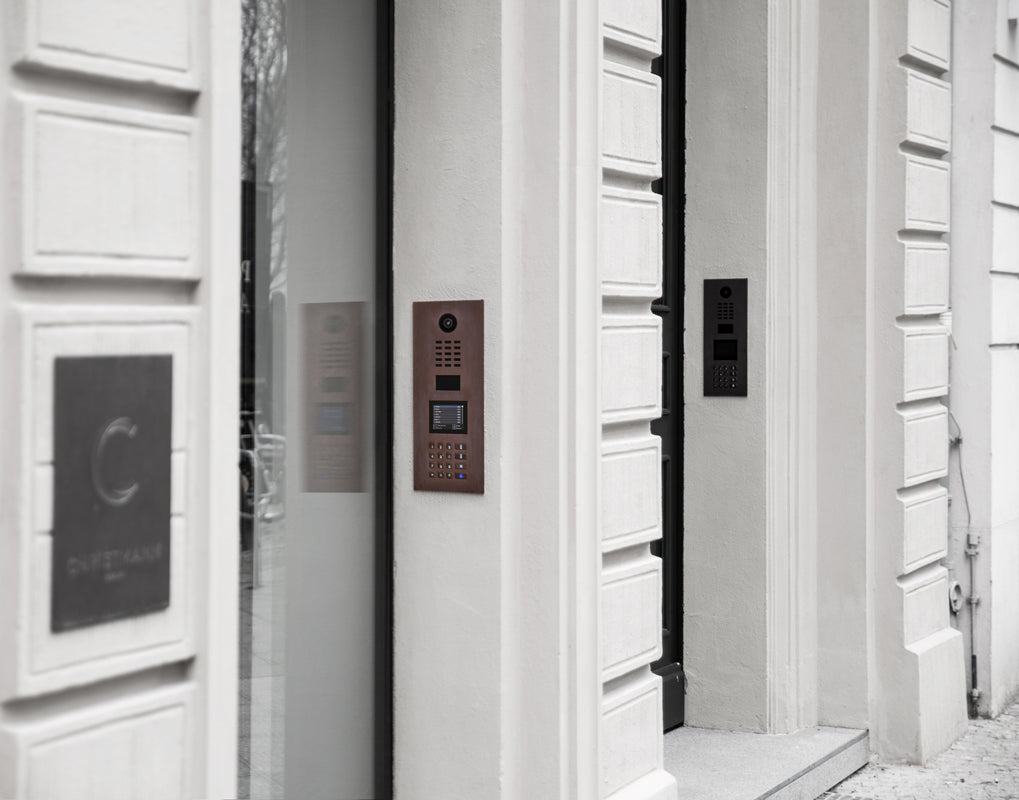 Bronze video door station mounted on wall with camera and keypad visible