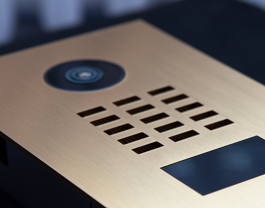 Gold IP video door station faceplate with camera lens and speaker grille