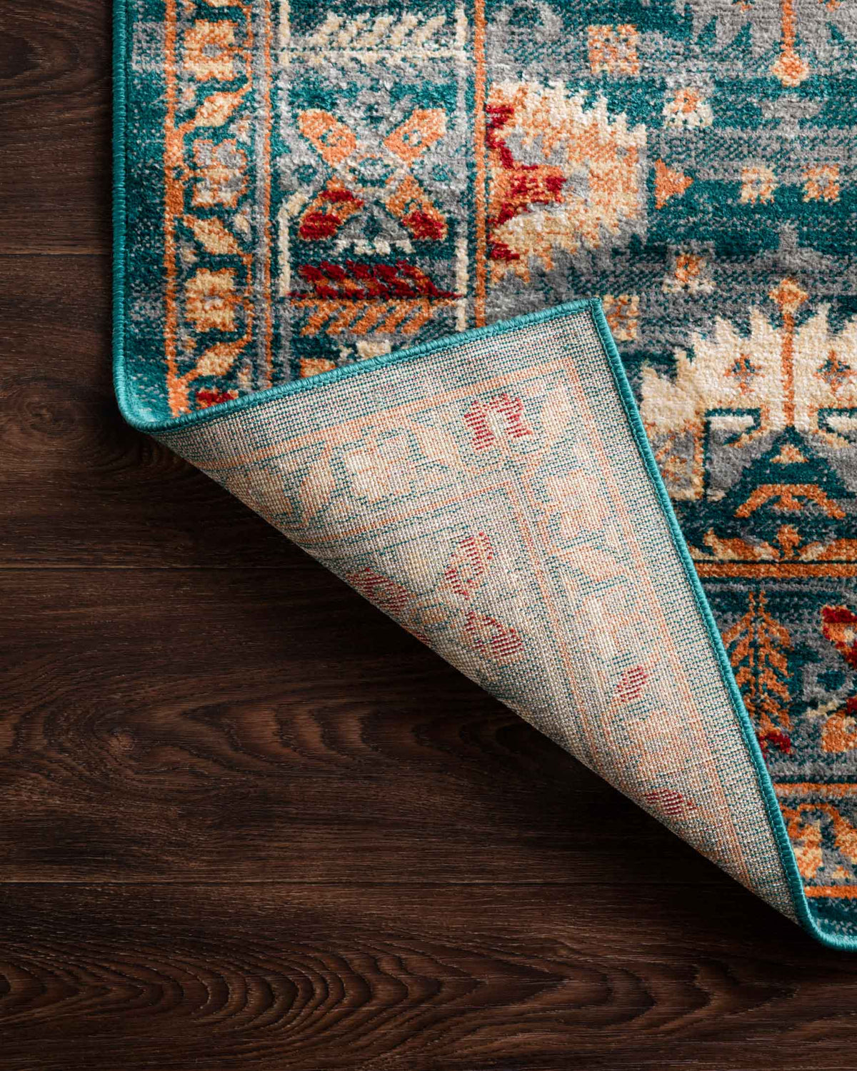Lagoon patterned power-loomed rug showing rolled corner on wood floor