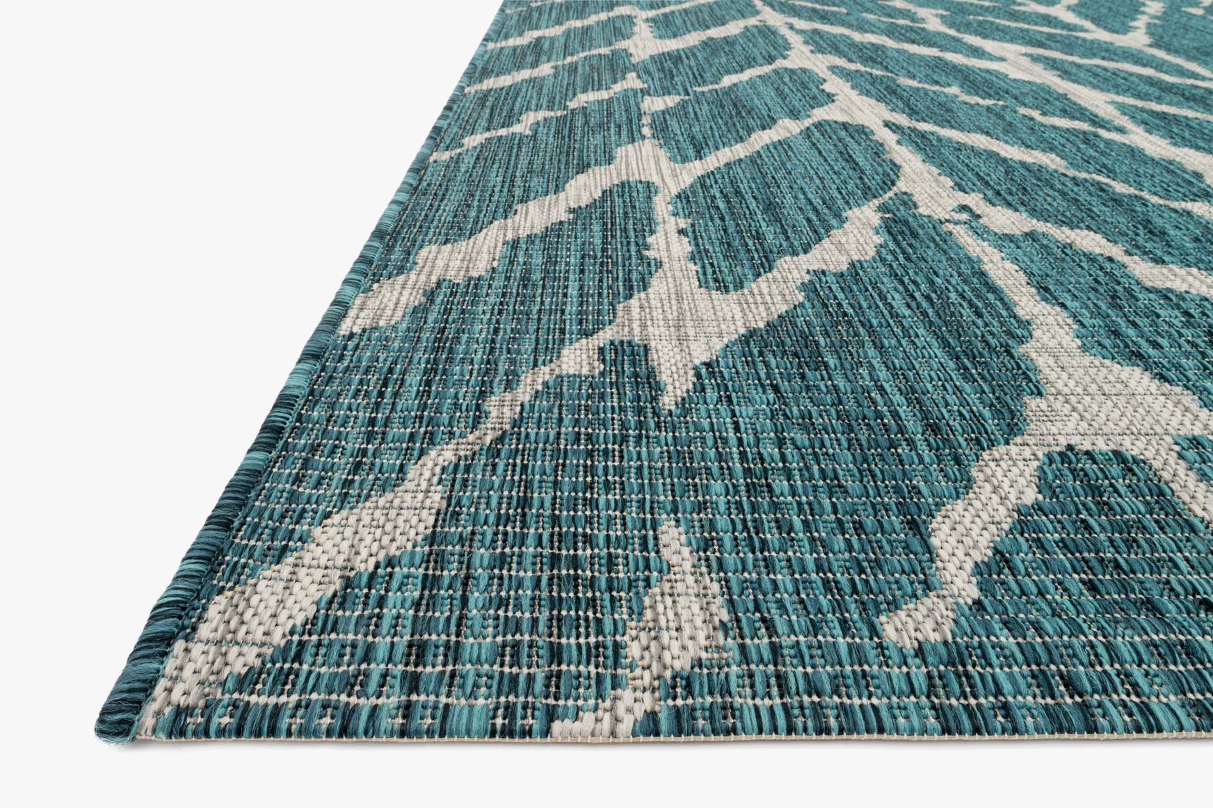 Teal and grey rug corner with white chevron motif and flat woven texture
