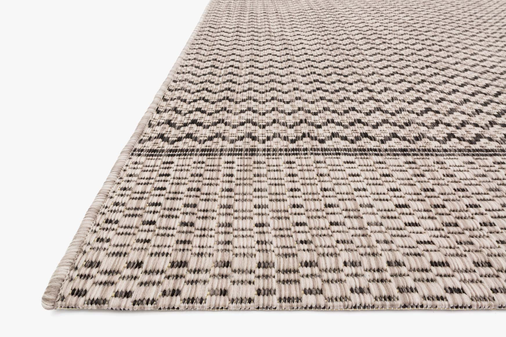 Close-up of grey and black chevron indoor/outdoor rug, flatwoven with stitched edge