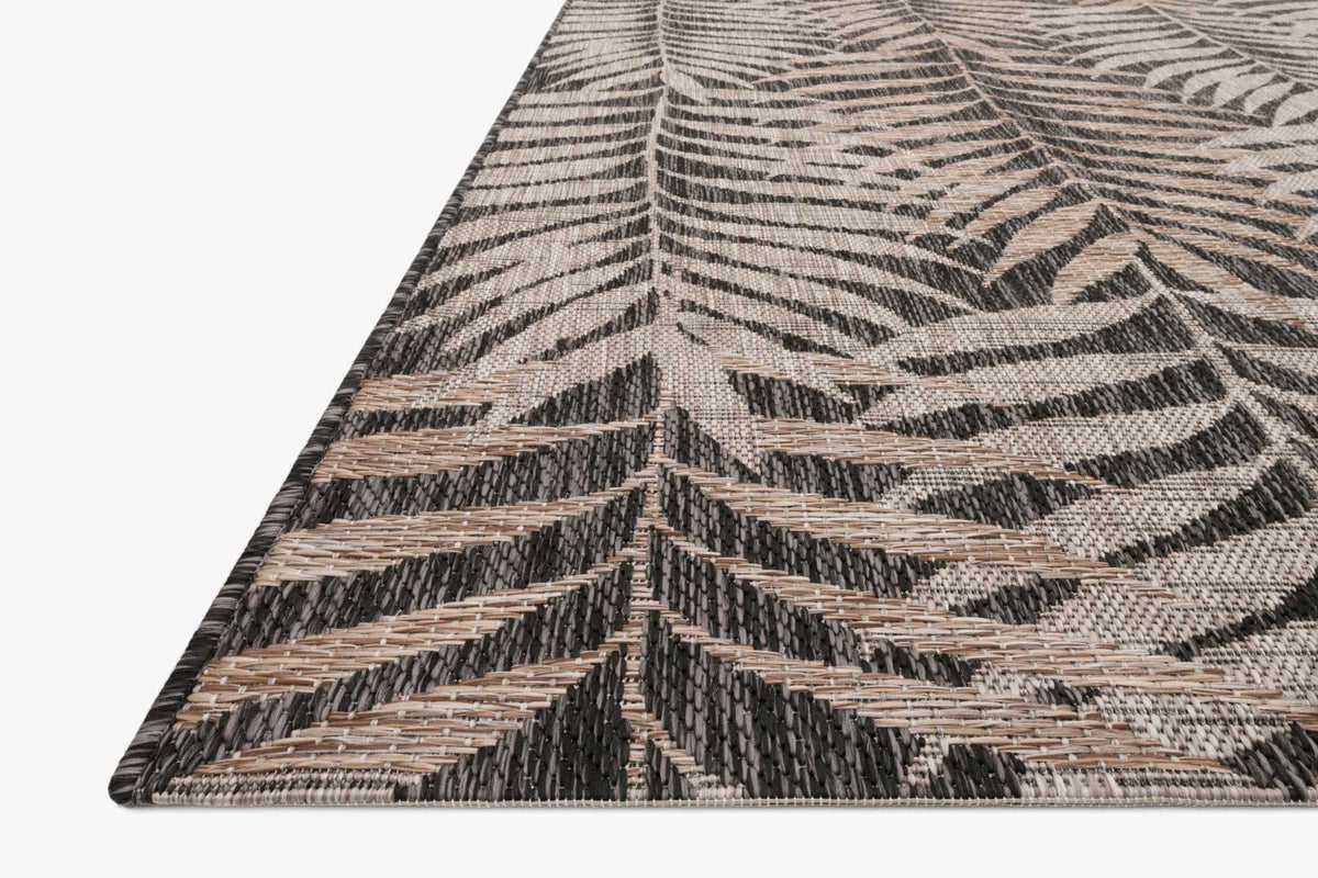 Indoor outdoor rug corner detail with layered leaf pattern in beige and black