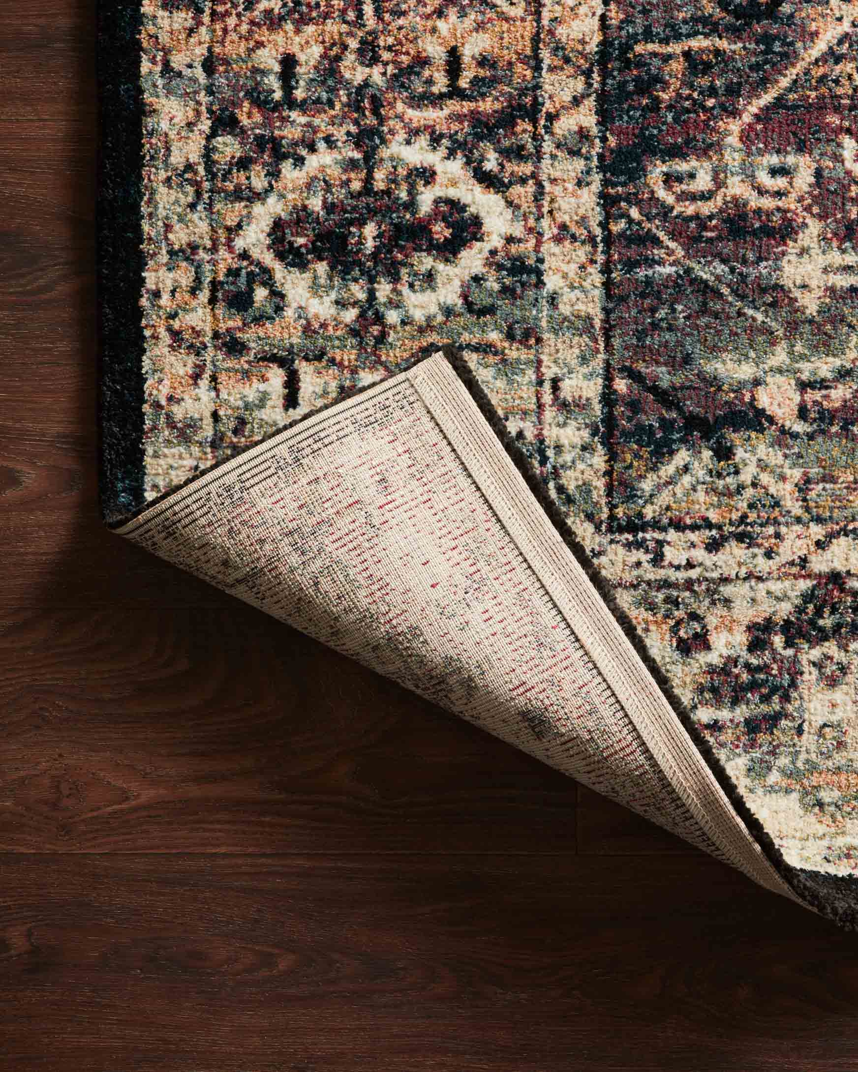 Power-loomed rug rolled to show thick pile and woven backing; ink and cream pattern