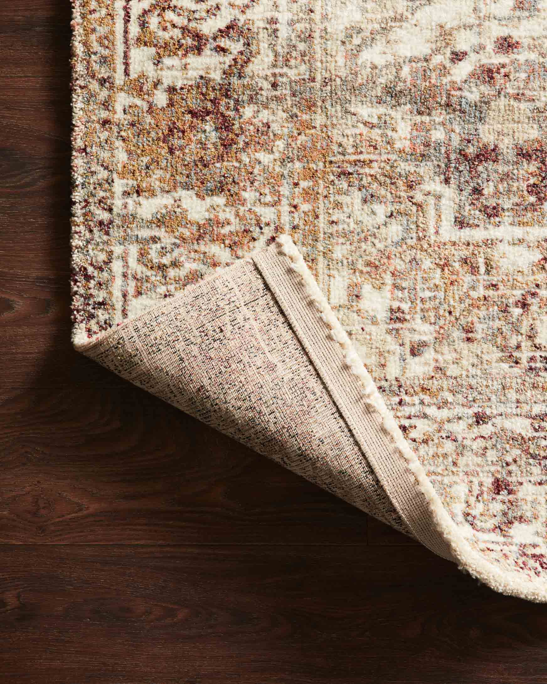Folded corner of ivory power-loomed rug with textured backing and border detail