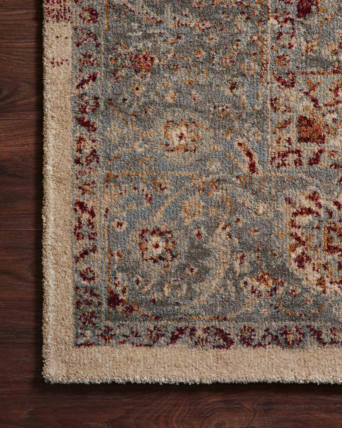 Close-up of slate blue rug pile with rust-red and beige distressed pattern