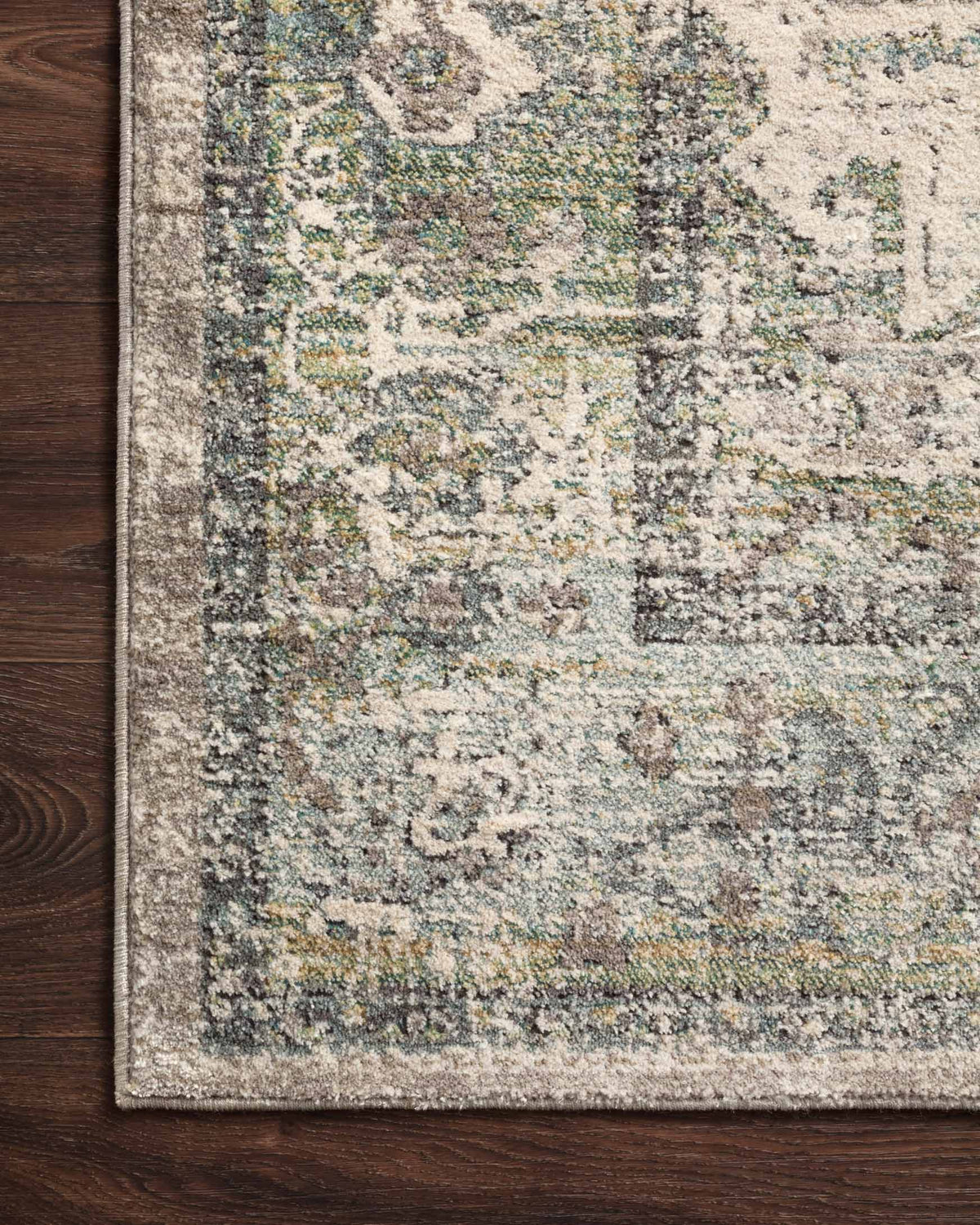 Power-loomed area rug with textured abstract pattern, beige base with green-blue accents and border