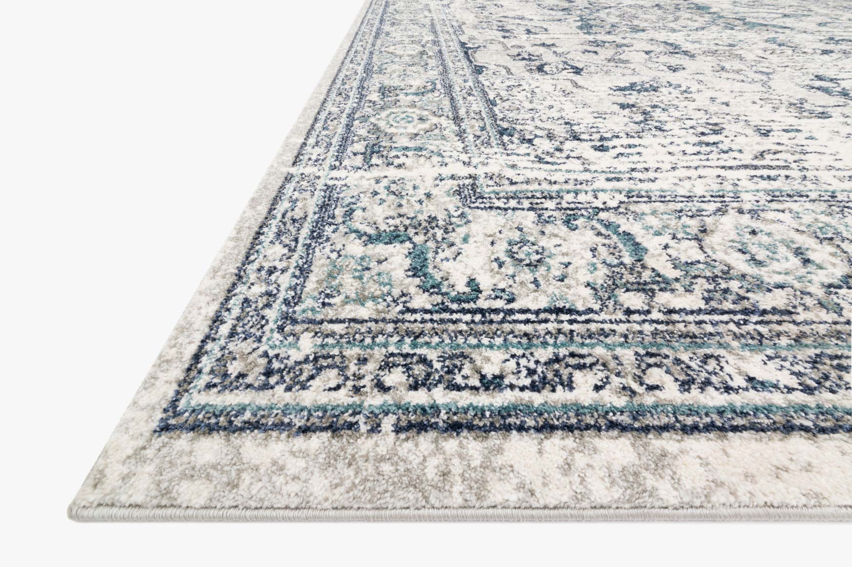 Corner view of traditional area rug with distressed blue pattern and light green highlights