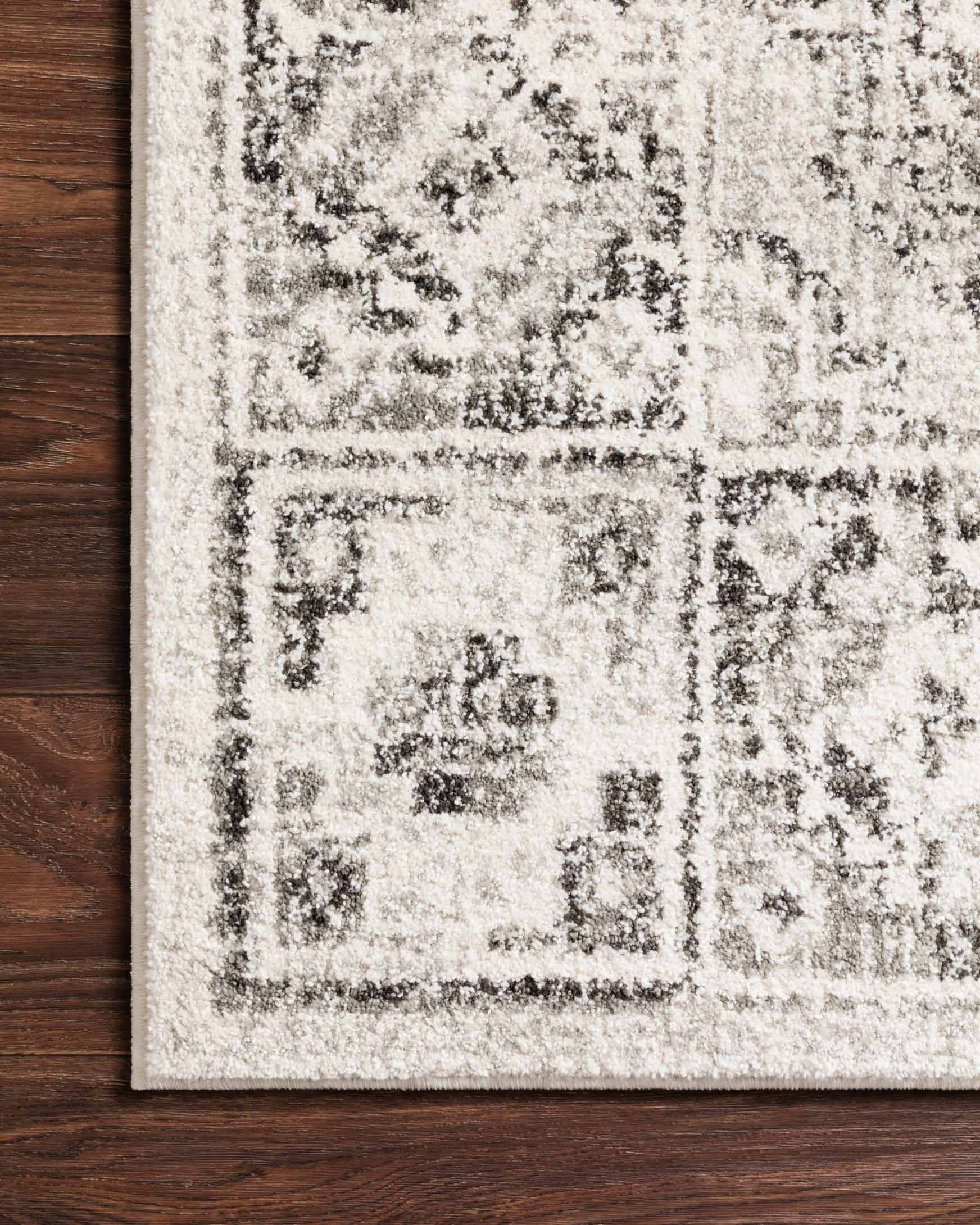Ivory and charcoal traditional rug close-up with textured pile and ornamental square motifs