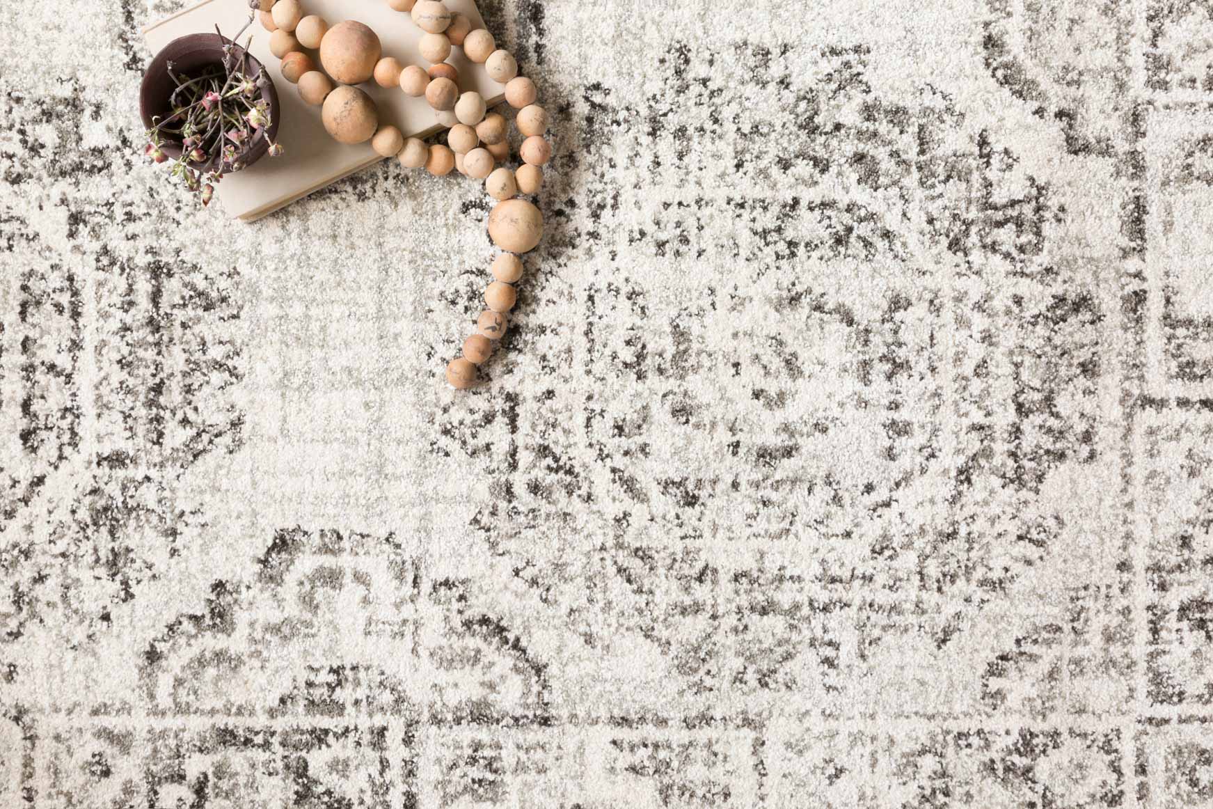 Ivory and charcoal distressed rug surface with speckled texture and geometric pattern