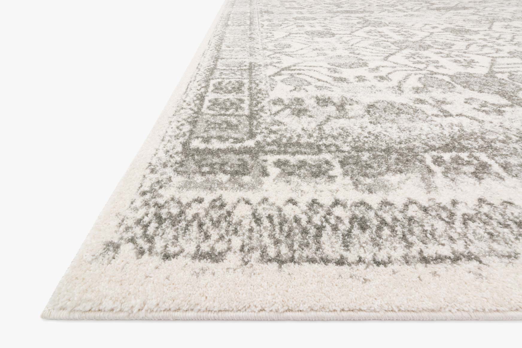 Ivory and grey rug corner with distressed geometric motif and short textured pile