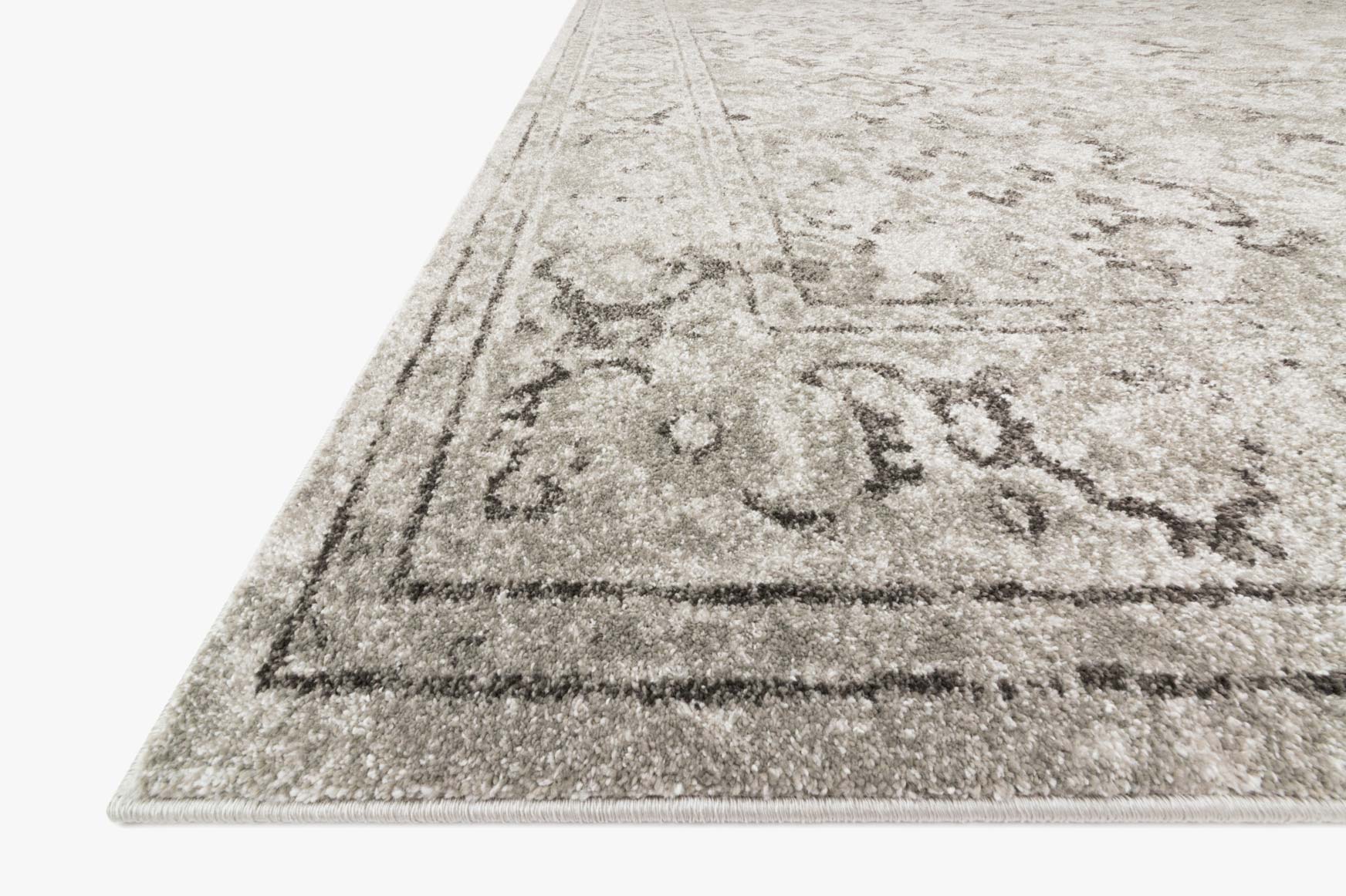 Silver-grey rug corner view with distressed scroll pattern and low-pile texture
