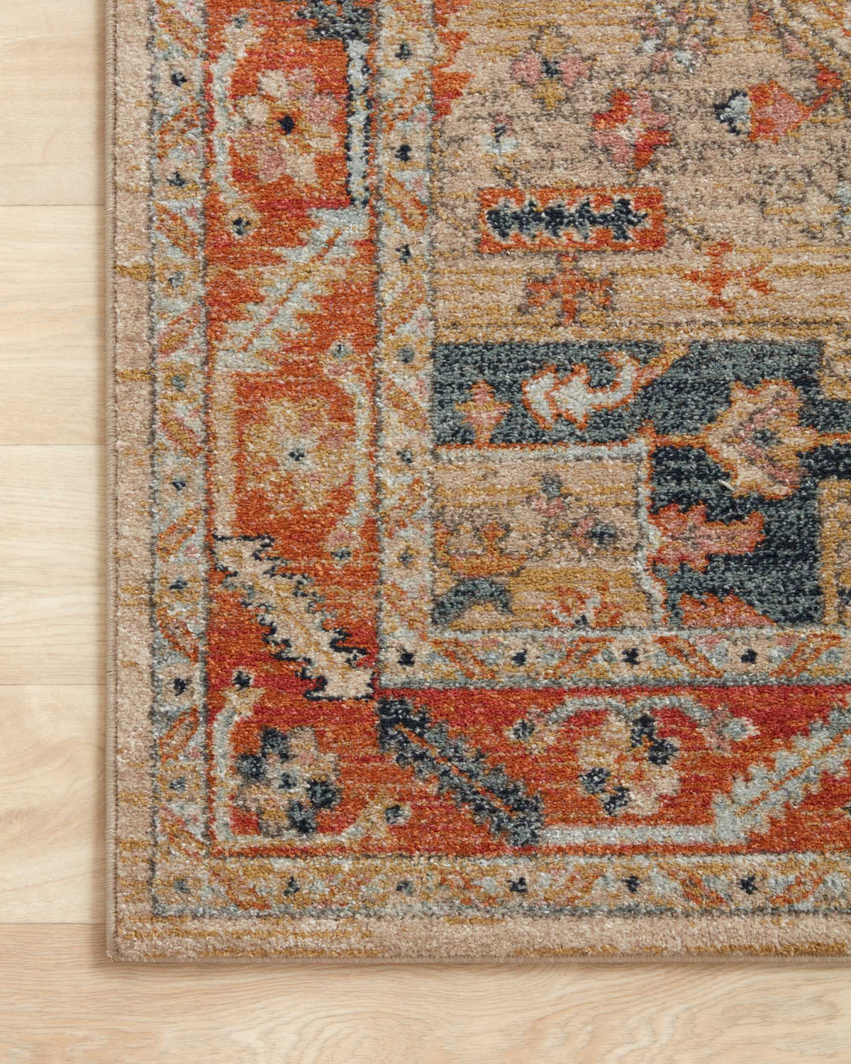 Edge close-up of power-loomed rug with distressed motif pattern in sand, rust, and navy blue