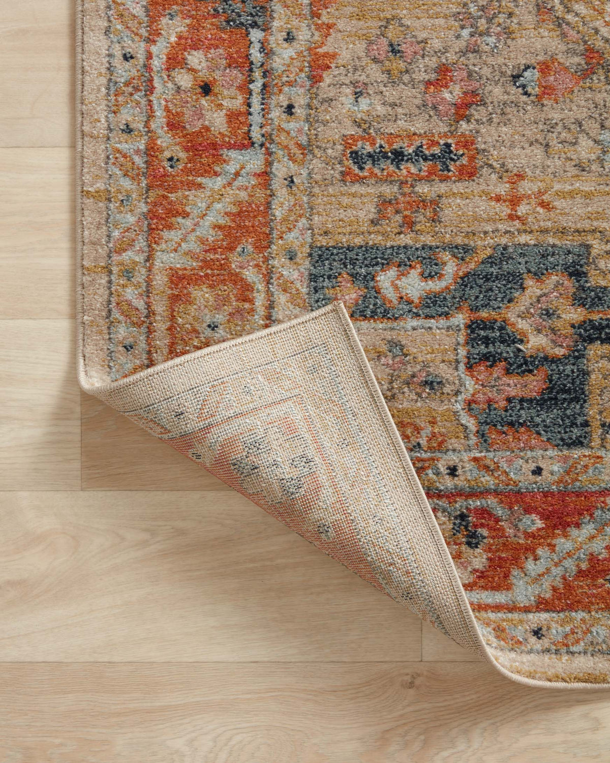 Diagonal view of transitional area rug showing distressed pattern and low-pile texture in sand hues