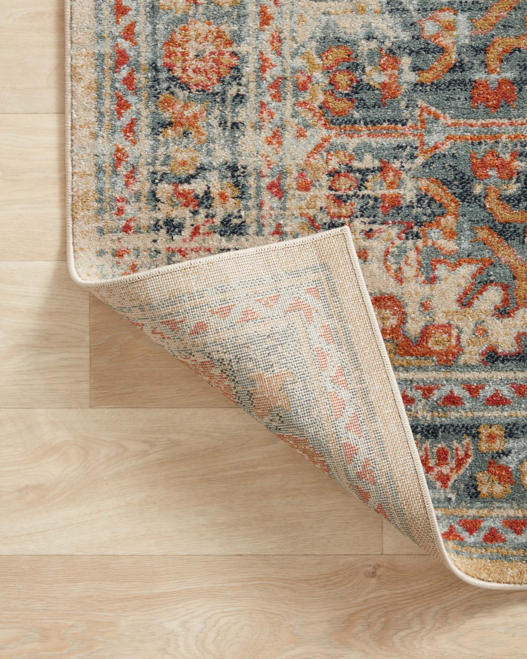 Transitional rug edge shown from the side, mist blue and orange patterned surface