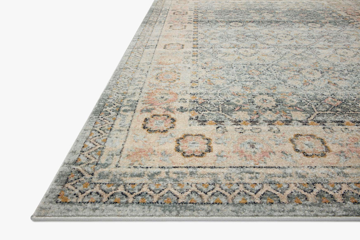 Corner view of sky blue area rug with distressed pattern and decorative border