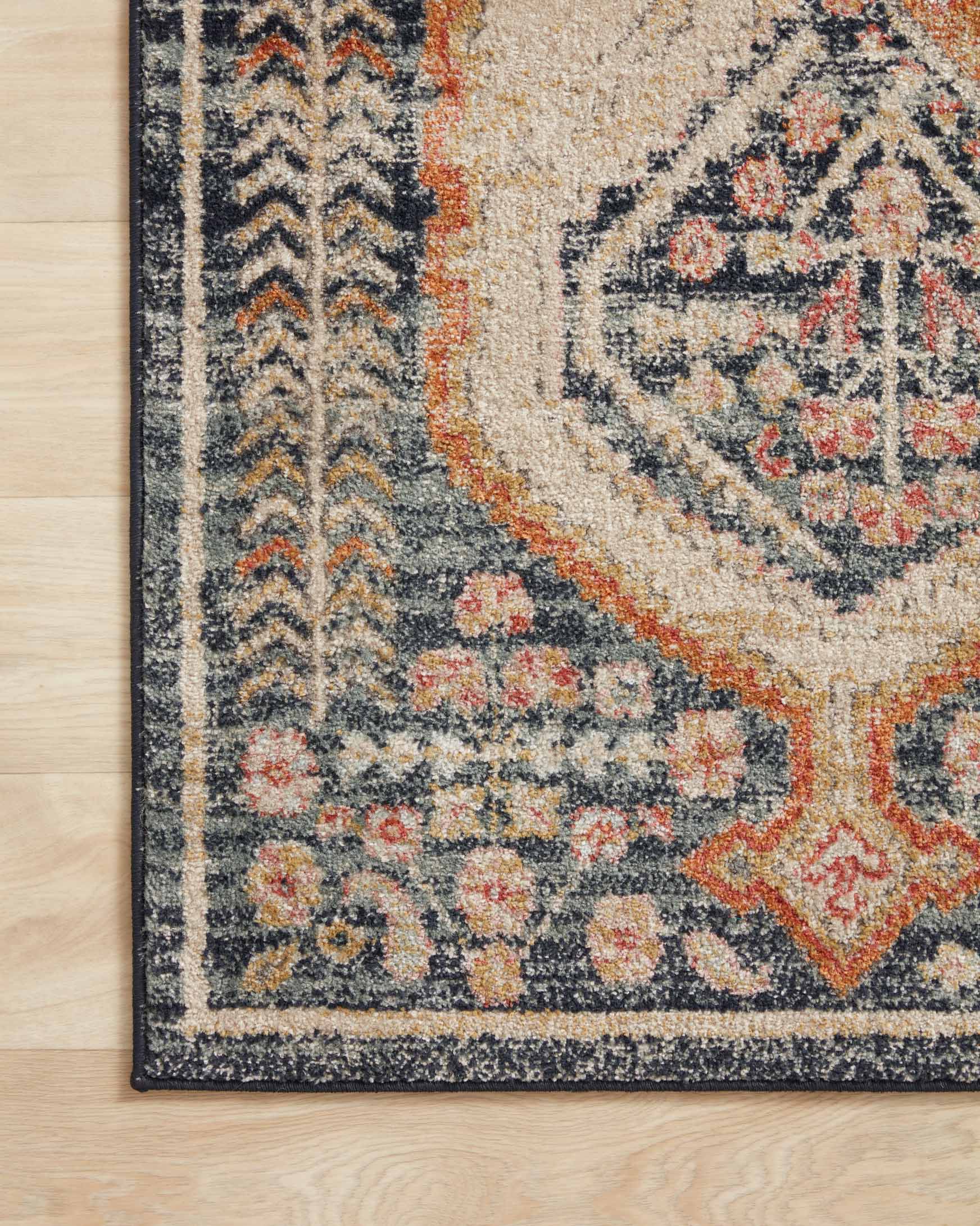Detail of navy and beige rug edge with orange geometric accents on patterned field