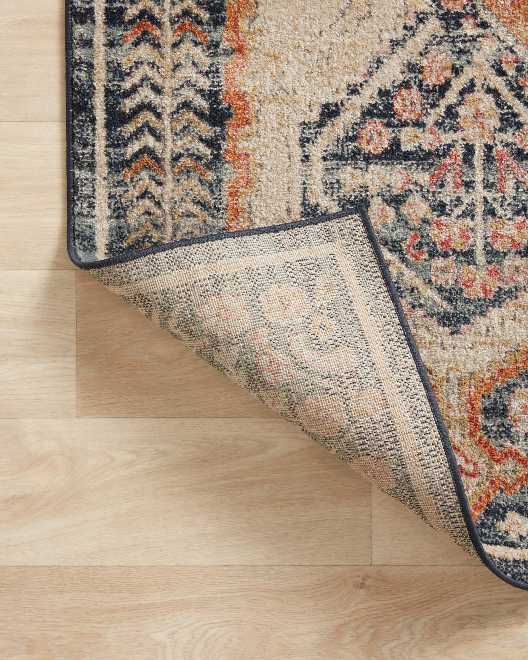 Area rug corner showing textured underside and navy binding edge