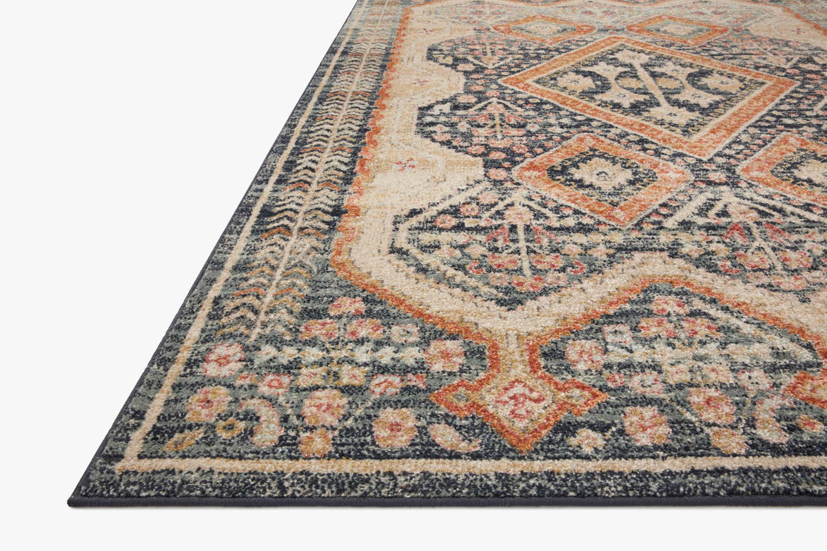 Close-up corner of navy, beige, and orange geometric area rug with patterned border