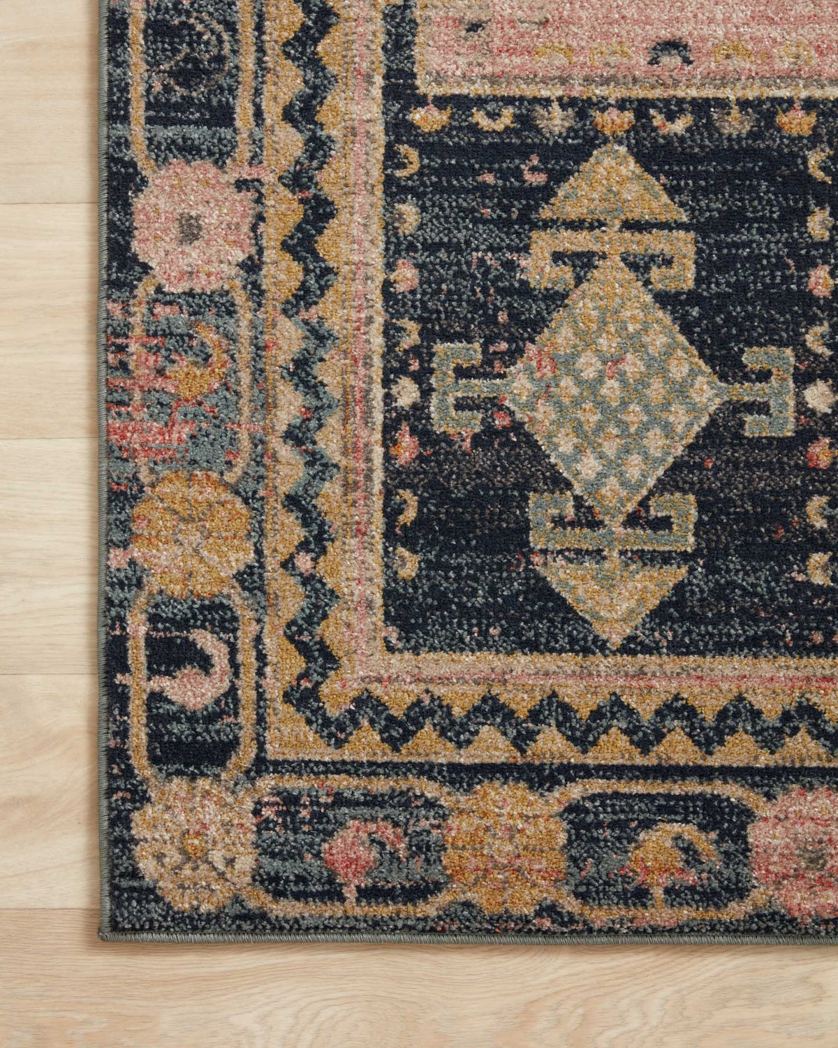 Close-up of rug section with diamond and star motifs in rose pink and dark navy.