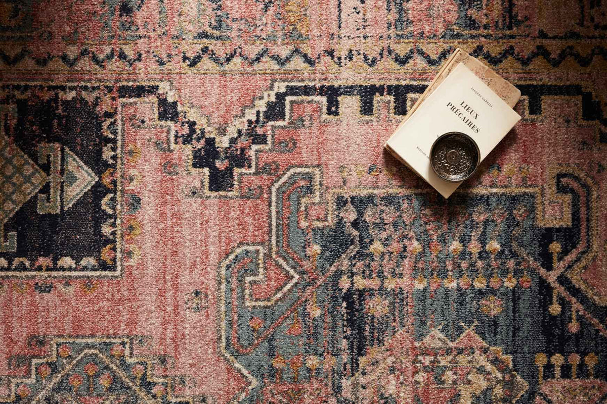 Close-up of transitional rug texture with rose pink and dark navy geometric motifs.