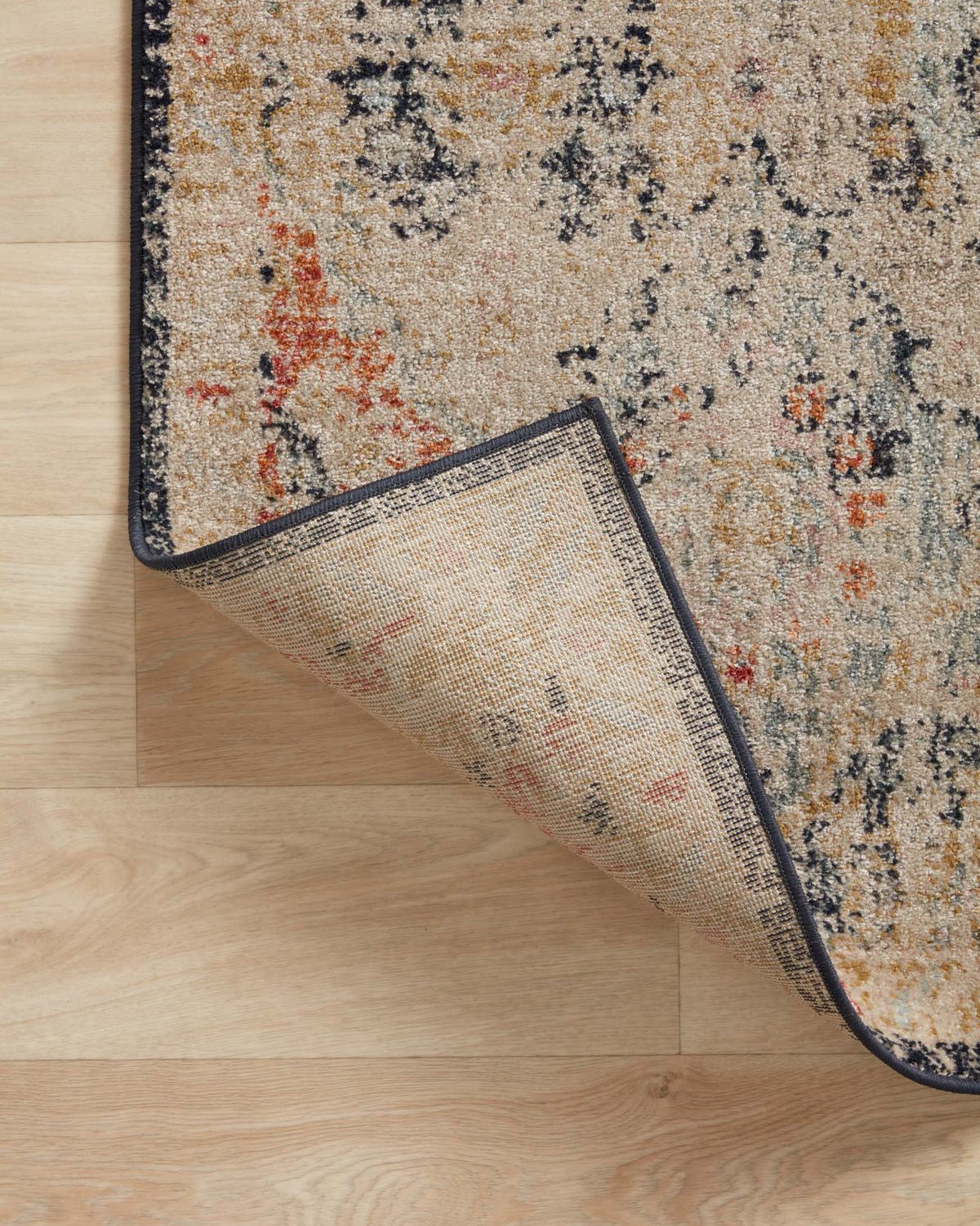 Transitional power-loomed rug edge with dark binding and woven underside visible