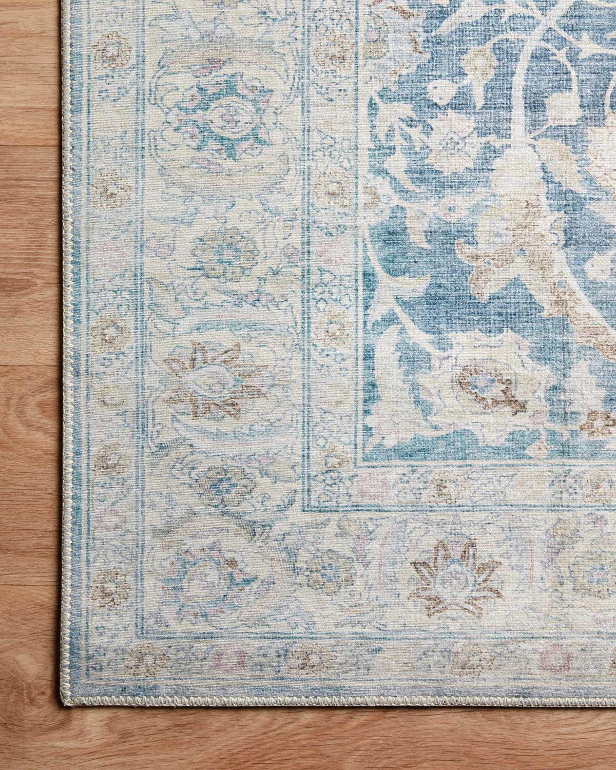 Traditional power-loomed rug close-up showing antique cream and sky blue floral panel design.