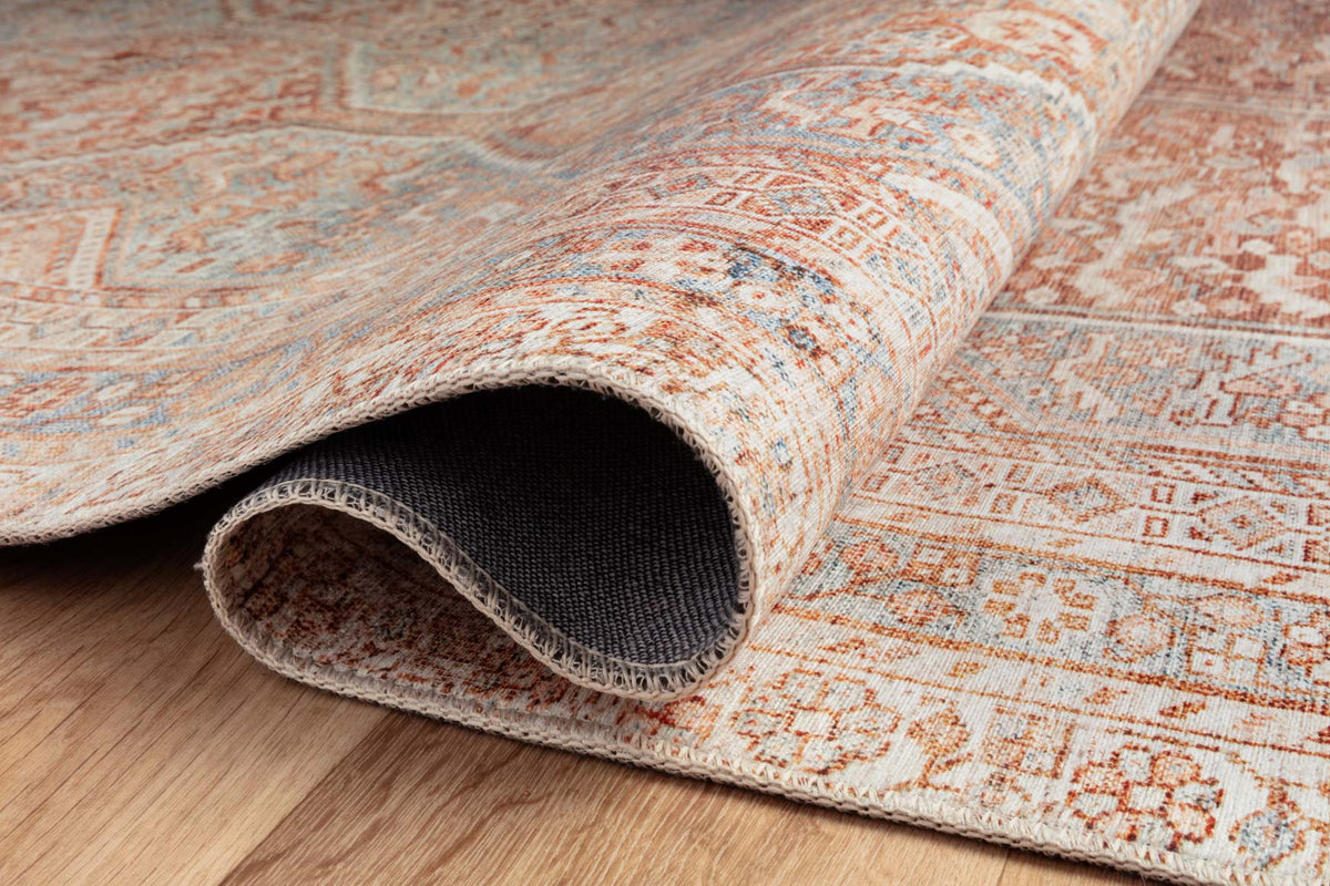Rolled edge detail of tangerine and mist geometric rug, textured flat weave
