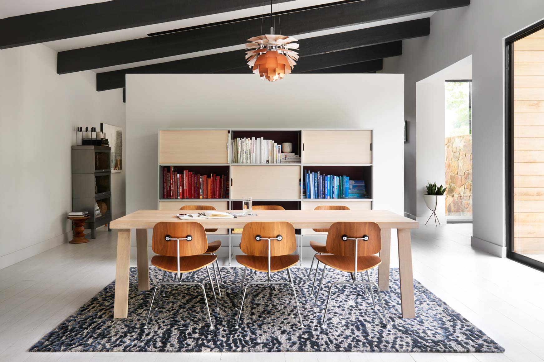 Steel and blue hand-tufted area rug centered under dining table and chairs.