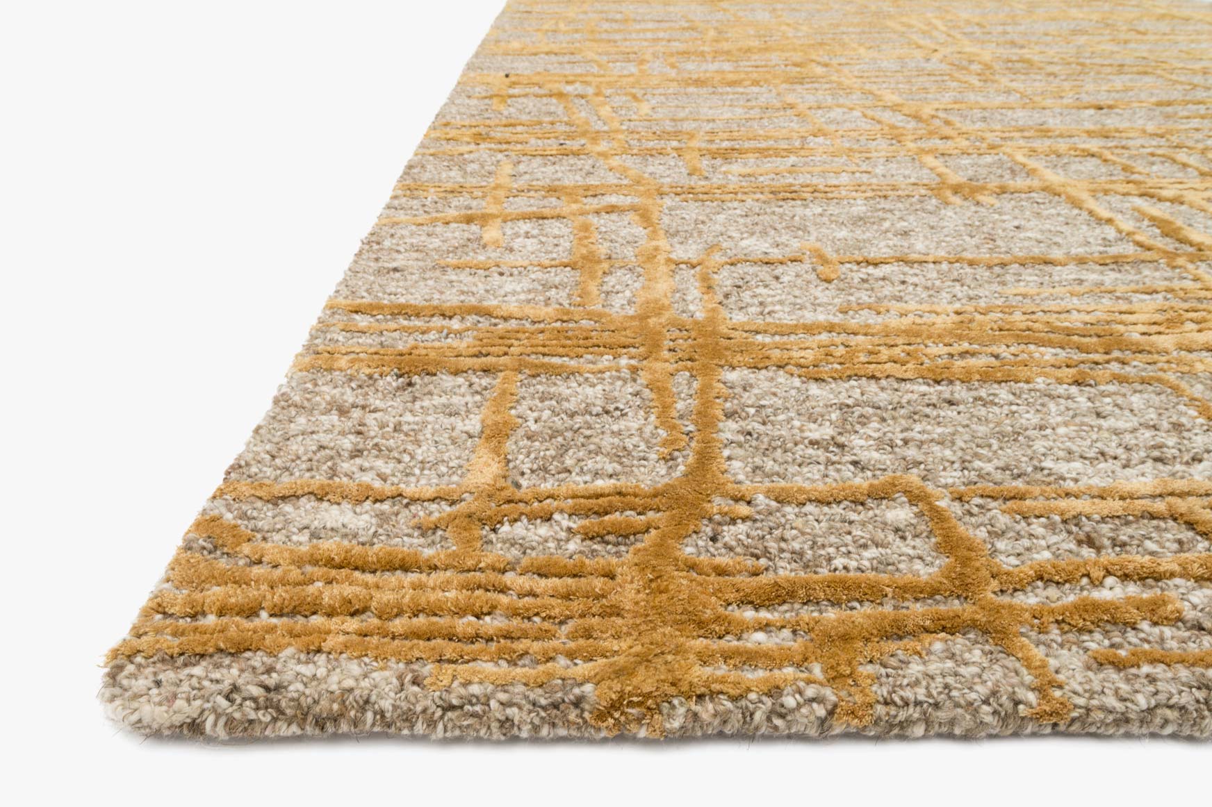 Corner detail of natural beige and gold hand-tufted rug with textured abstract pattern