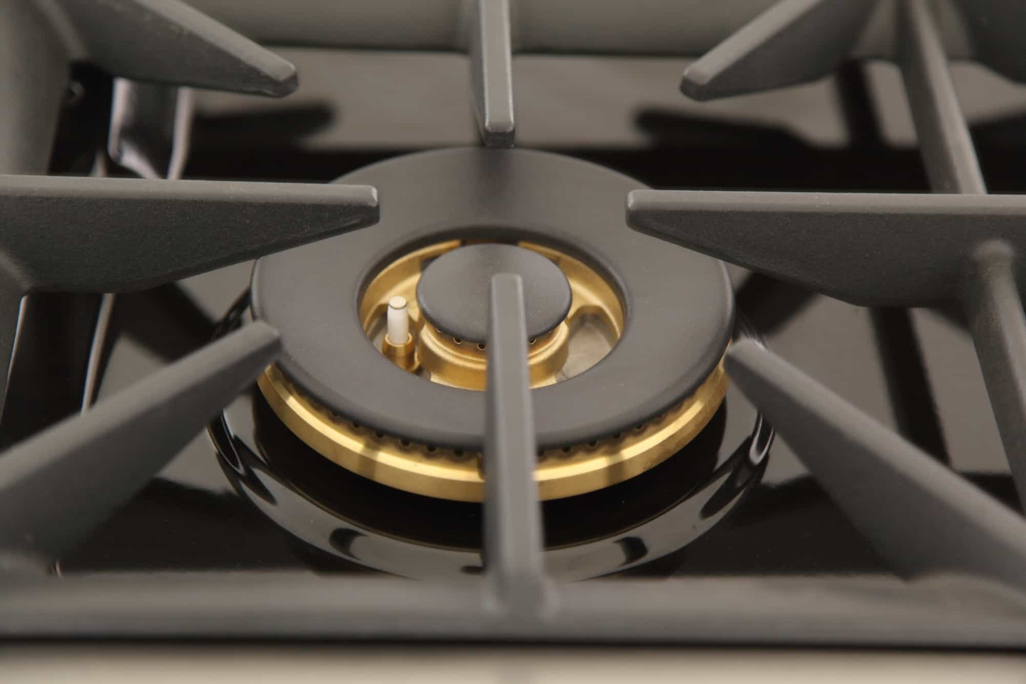 Close-up of single gas burner with black grate and gold-toned ring