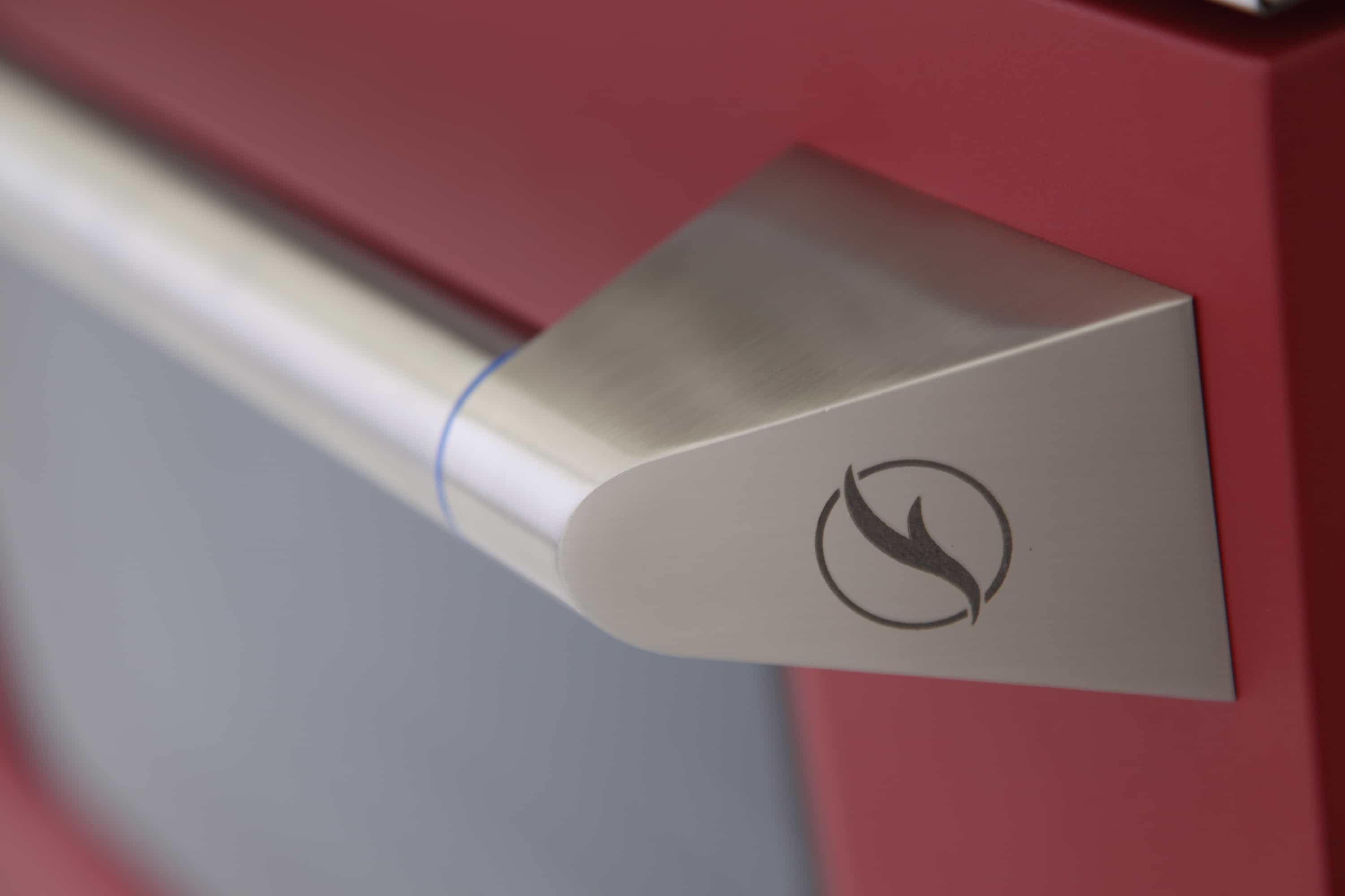 Stainless control panel handle with flame icon on a red pro-style dual fuel range