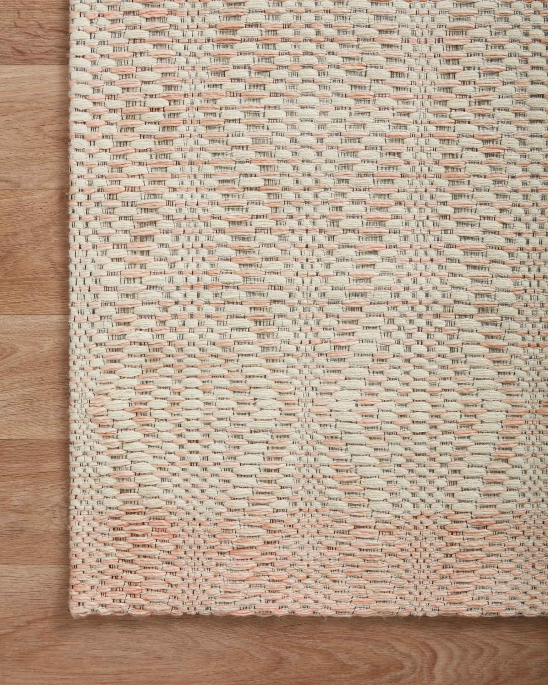 Ivory and blush hand-woven rug with textured diamond pattern and flat woven edge