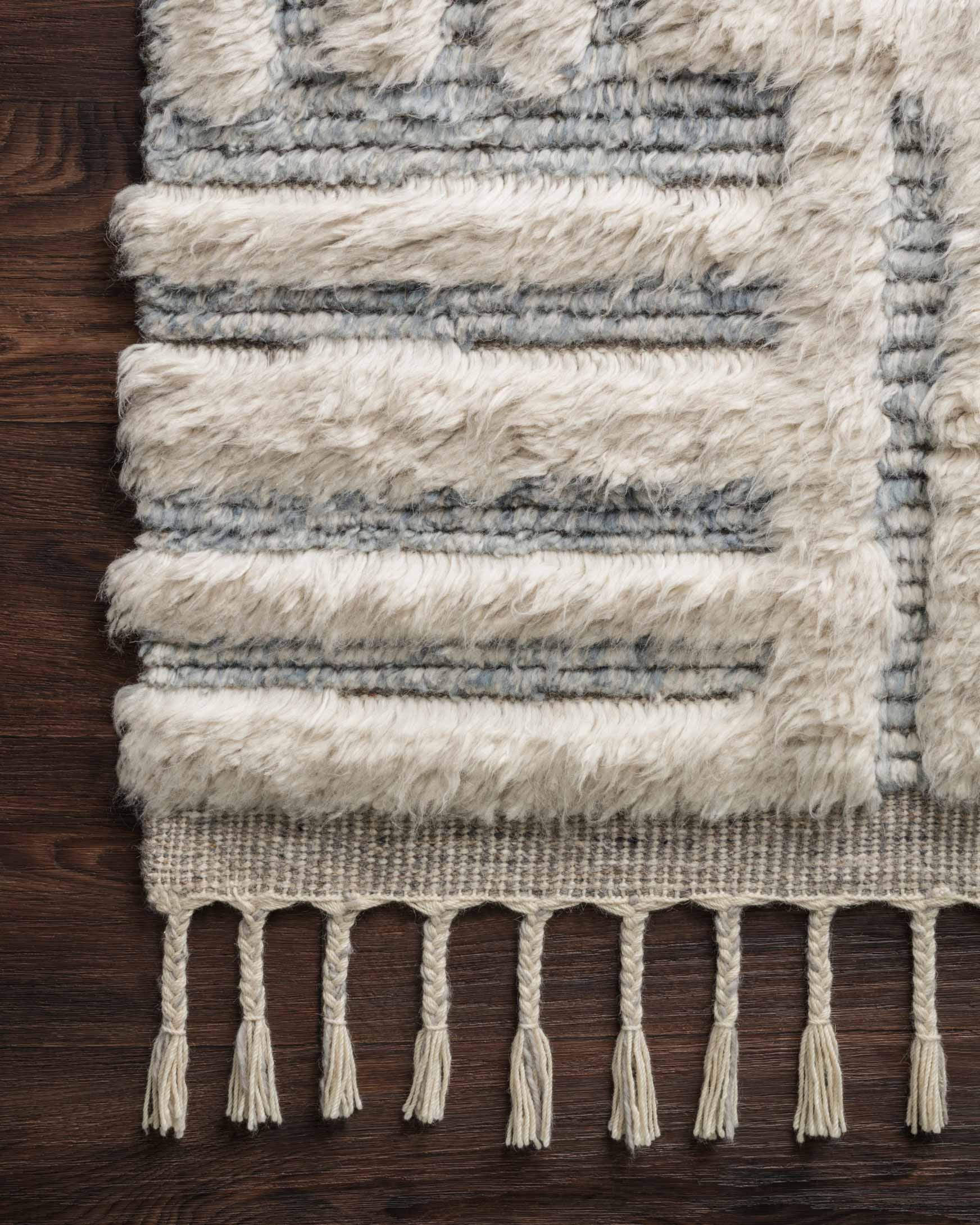 Ivory and sky textured rug border with layered stripes and dangling tassel fringe