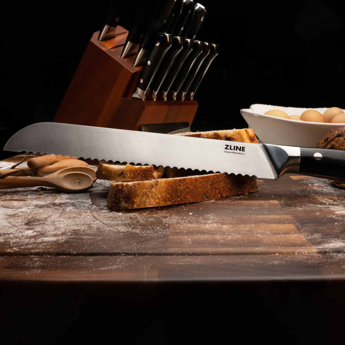 Stainless chef’s knife with black handle and serrated blade on wooden cutting board