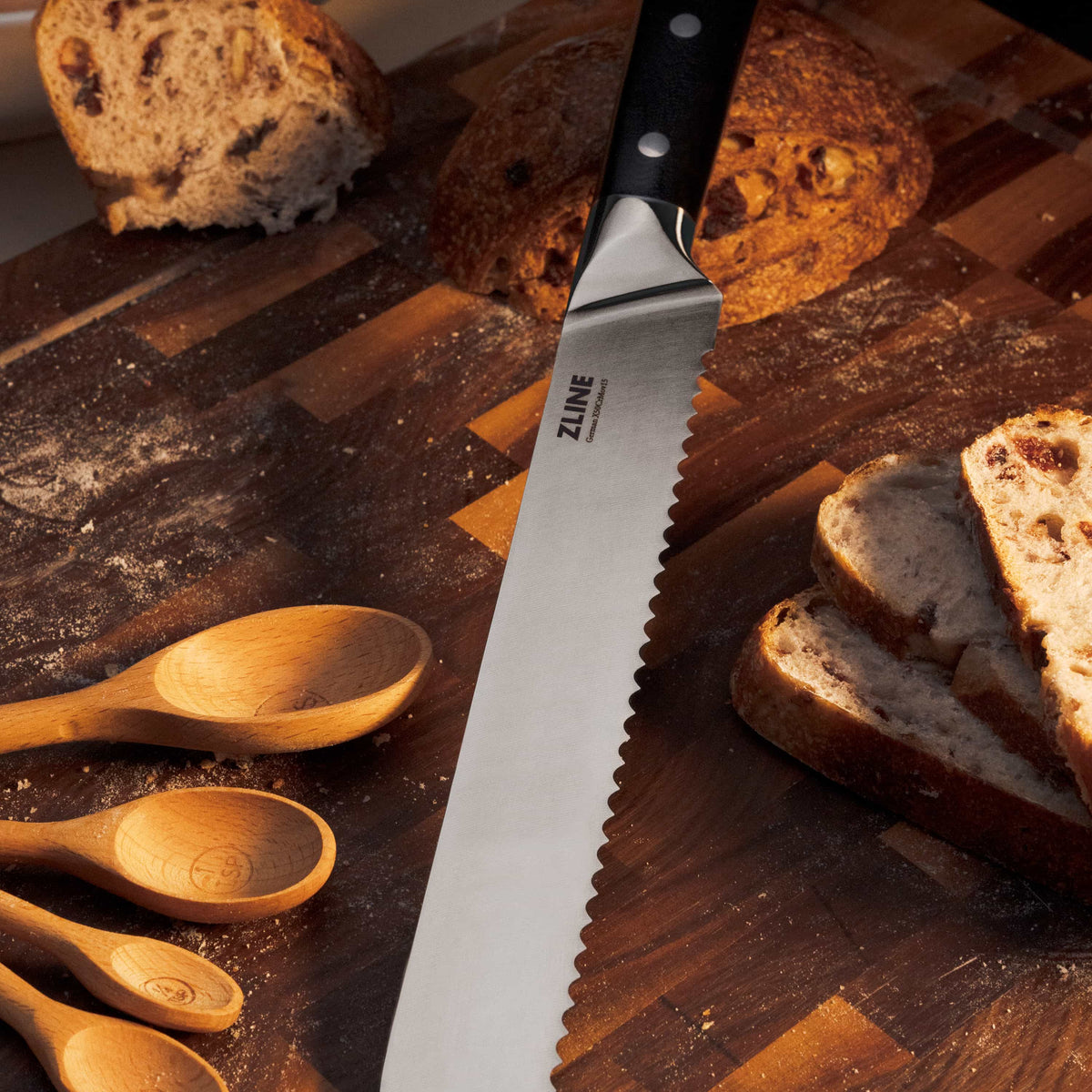 Stainless serrated knife with black handle beside sliced bread on wooden board