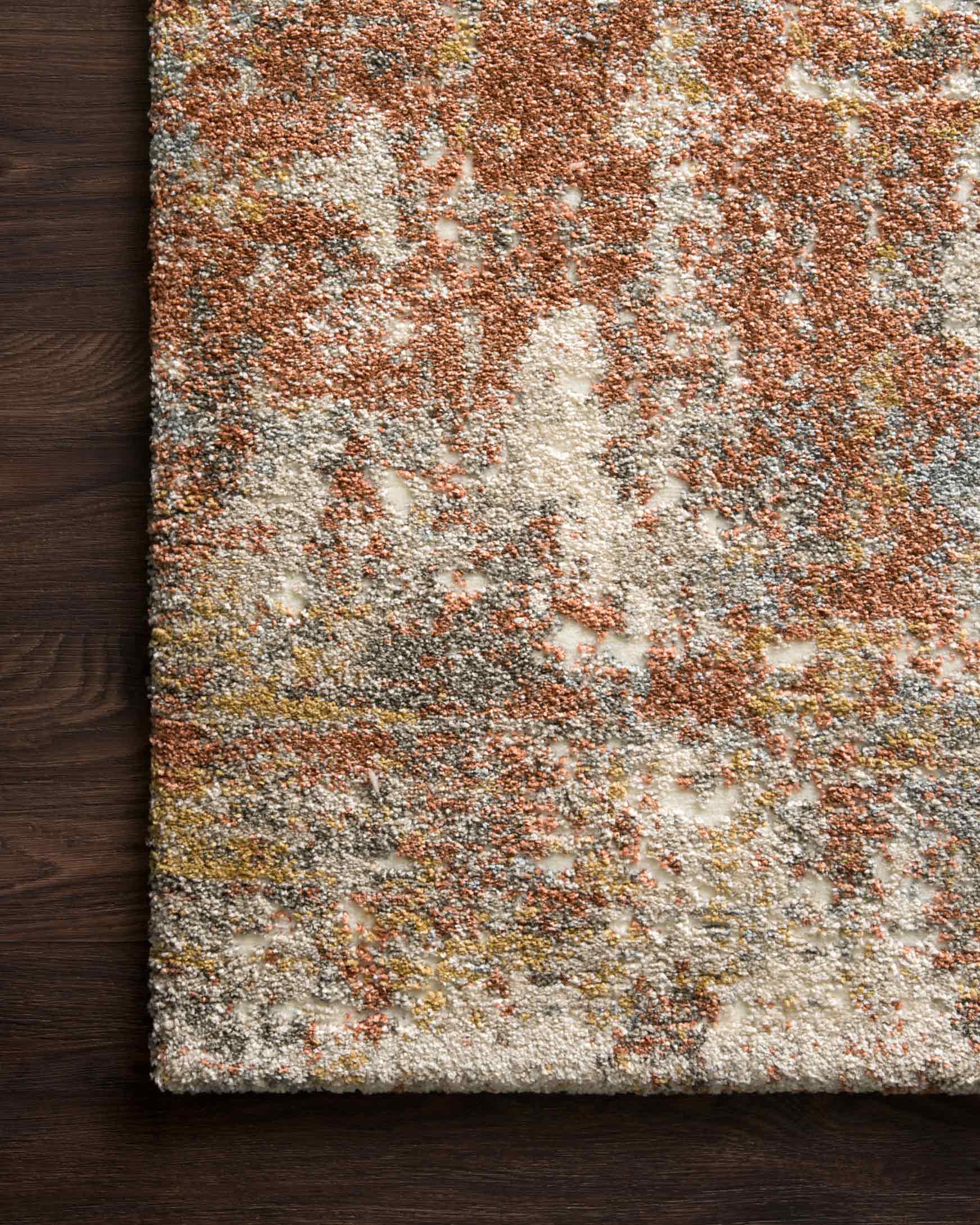 Abstract rust, cream, and gray rug with close-up short pile and mottled speckle texture.