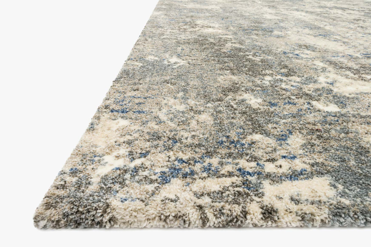 Slate-toned abstract rug corner with short textured pile and cream-blue speckles