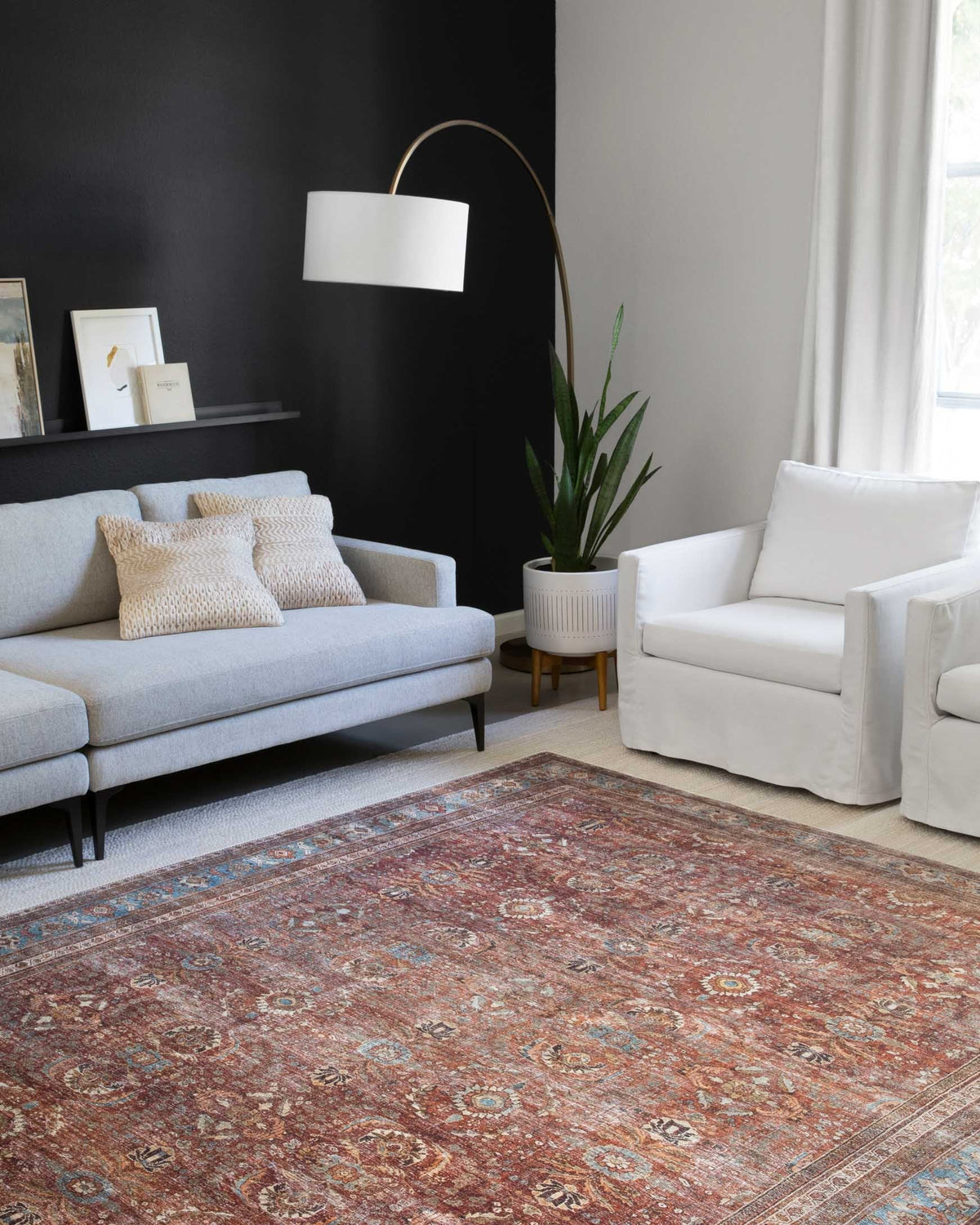 Brick and blue traditional area rug centered on the floor between modern sofas.