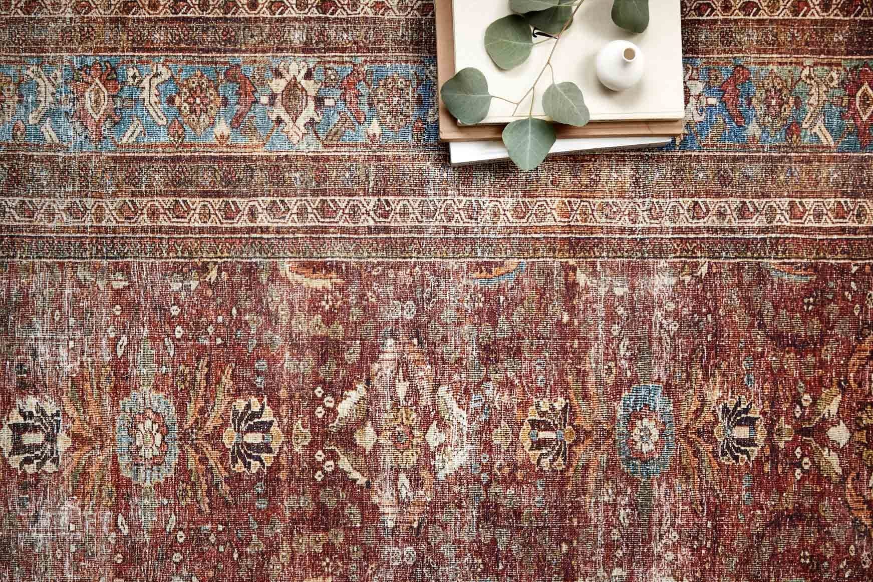 Close-up of brick and blue traditional rug pattern with dense motifs and trim border.